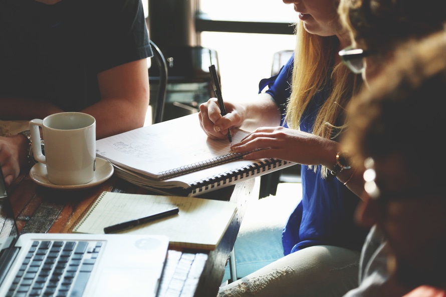 Réunion d'entrepreneurs PME travaillant sur les changements réglementaires en assurance, prise de notes et planification autour d'une table